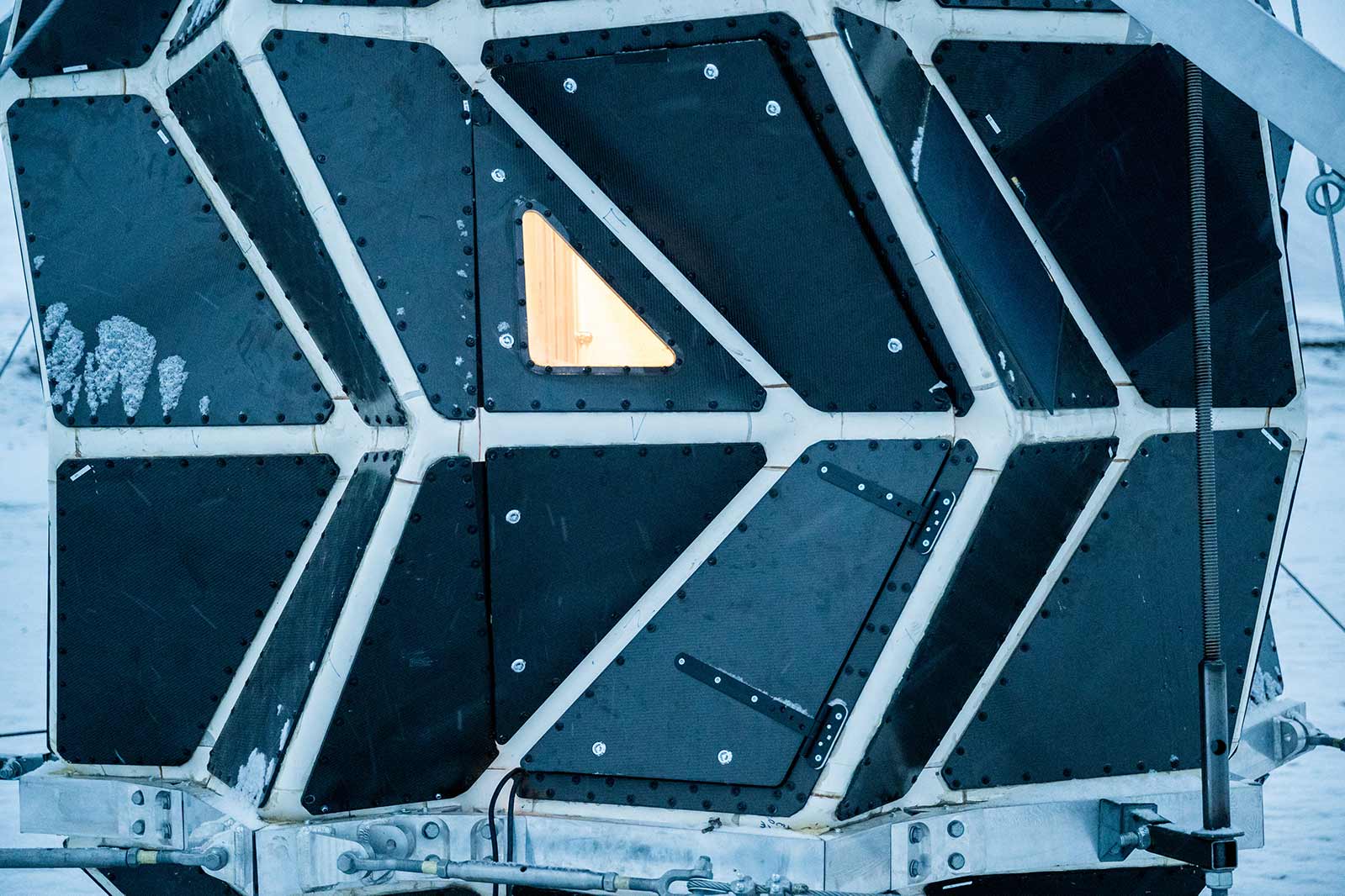 Closeup of the foldable door, with the only window in the structure, which reveals the warm safe home inside